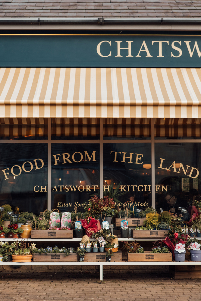 Chatsworth Kitchen - Food from the land, Estate sourced. Locally made. Yellow and white striped awning above plants.